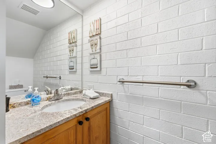 Built-in vanity with wood cabinetry, integrated sink, and stone-finish countertop