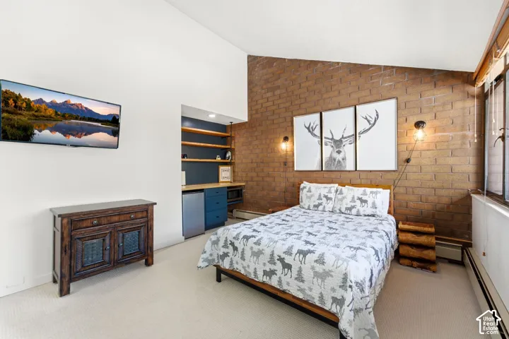 Exposed brick accent wall, built-in shelving, integrated desk area, and wall-mounted television
