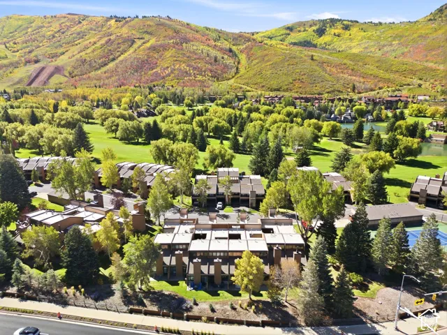 Residential community featuring multiple townhome-style buildings, mature trees, and an on-site tennis court