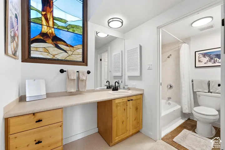 Stained glass window, wood vanity with integrated sink, built-in drawers, and a tub/shower combination