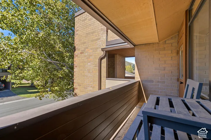 Balcony with wood-finish railing, brick exterior, and a built-in window