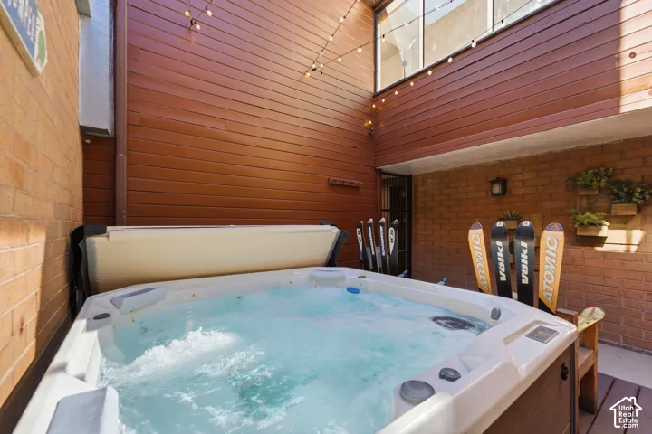 Spa-inspired soaking tub with integrated hydrotherapy jets and illuminated interior, anchored by a curved headrest panel