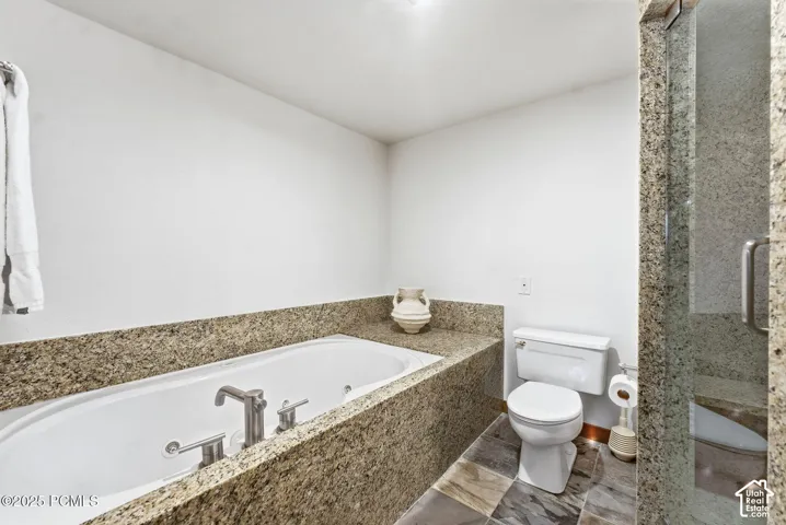 Built-in soaking tub with brushed nickel fixtures, surrounded by a stone-finish countertop
