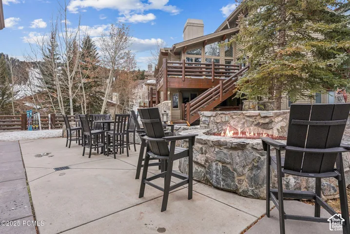 Patio featuring a built-in stone fire pit, extensive hardscaping, and multi-level wooden decking