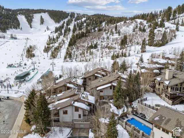 Mountain setting featuring ski slopes, residential buildings with pitched roofs, and a covered outdoor pool