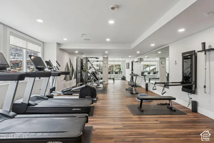 Spacious fitness area featuring wood-finish flooring, recessed lighting, and large windows
