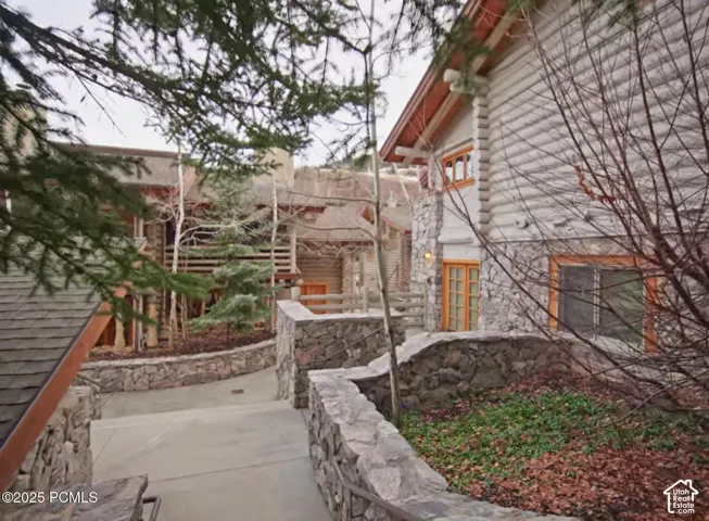 Log-style exterior with stone accenting, wood-frame windows, and a stone retaining wall