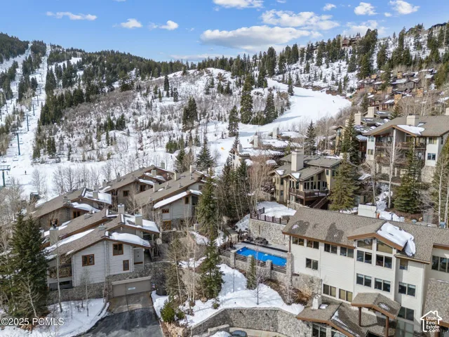 Mountain-side residences with a covered outdoor pool, surrounded by snow-covered terrain and mature evergreen trees