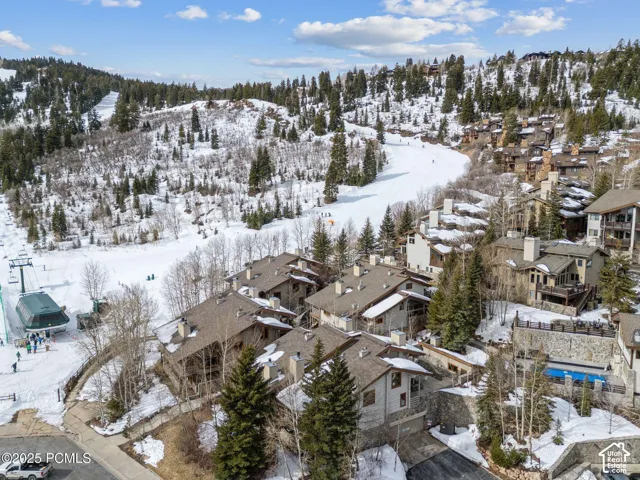 Aerial perspective of residences nestled into a snow-covered mountain landscape, featuring a ski slope and ski lift