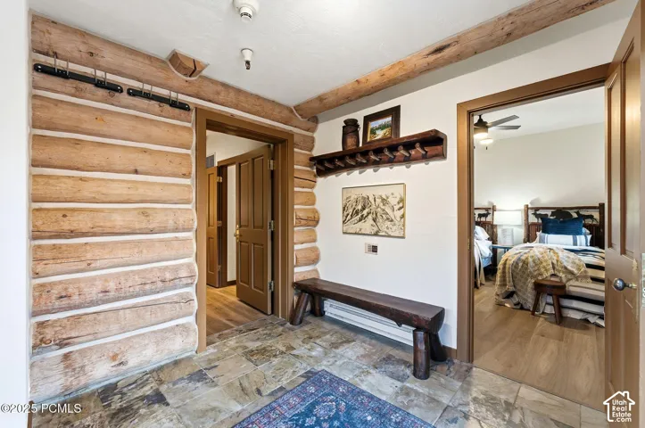 Rustic log wall construction, natural wood ceiling beams, stone tile flooring, and solid wood interior doors
