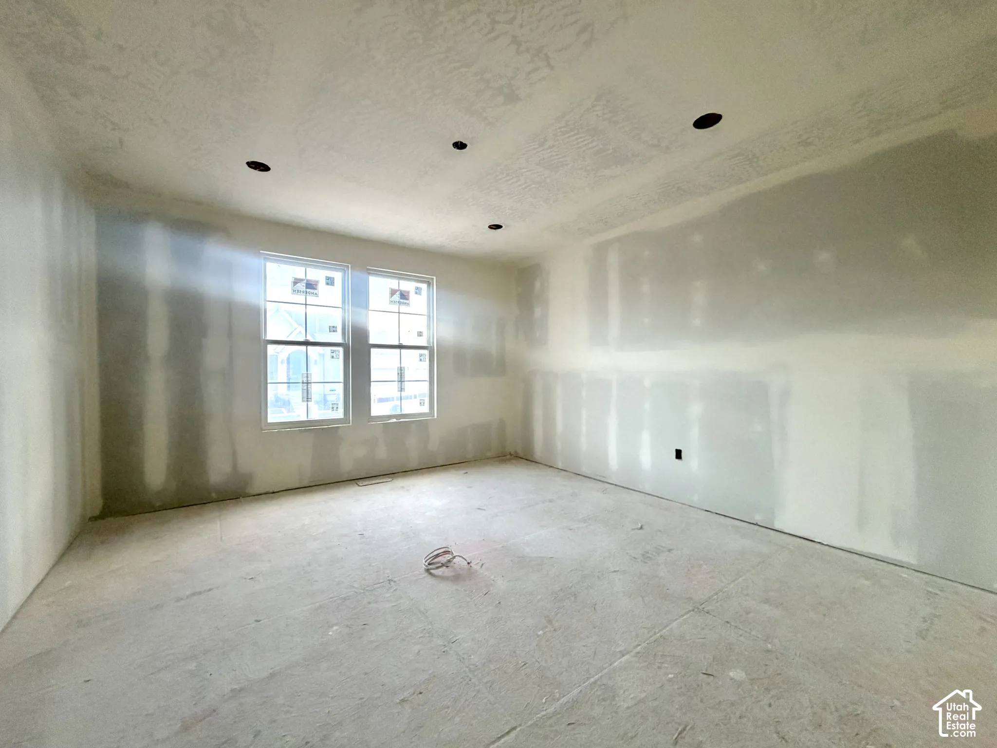 Unfinished interior space featuring two windows, recessed ceiling lighting, and exposed drywall