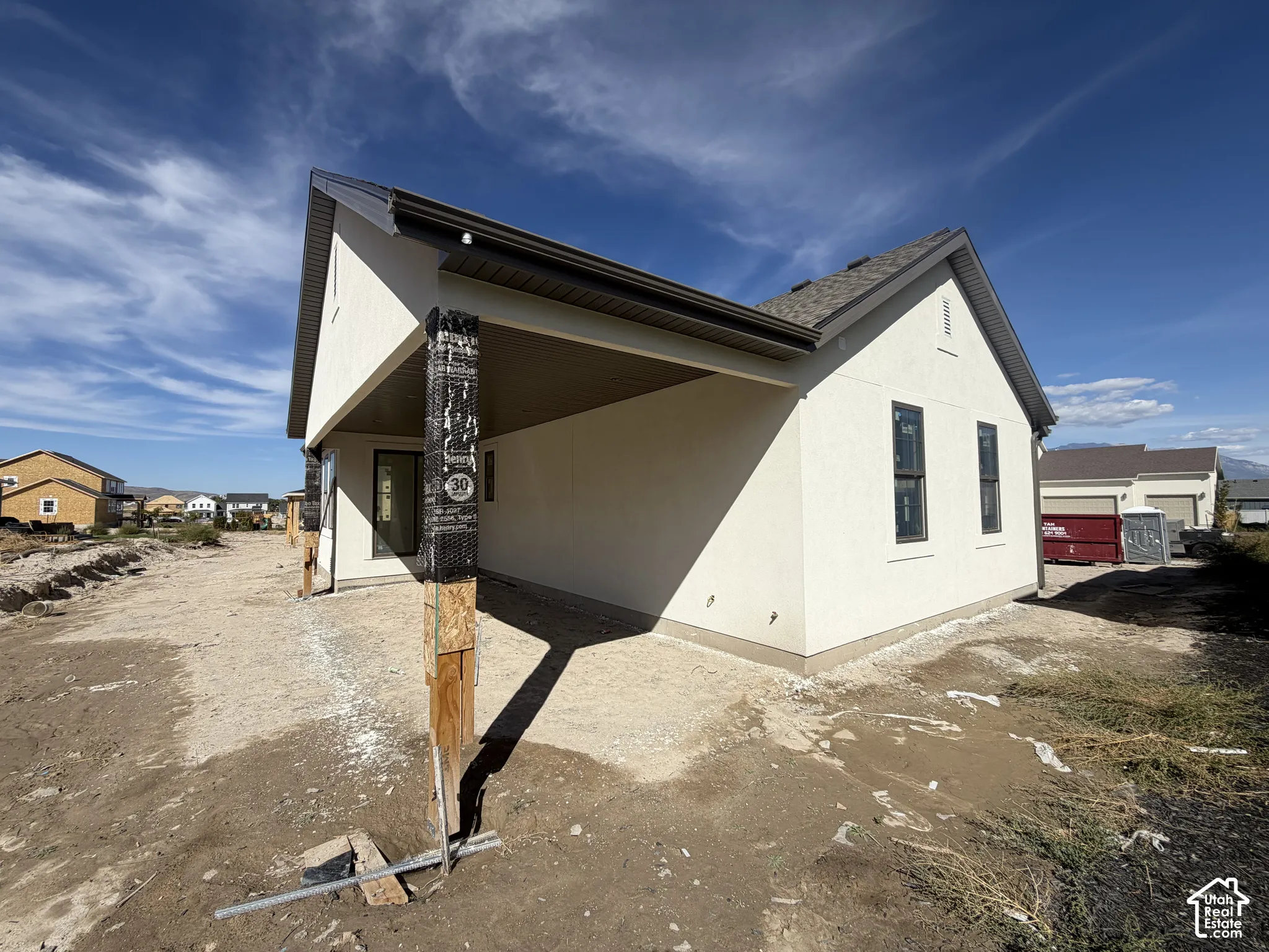Cream stucco exterior with dark trim and a covered patio area