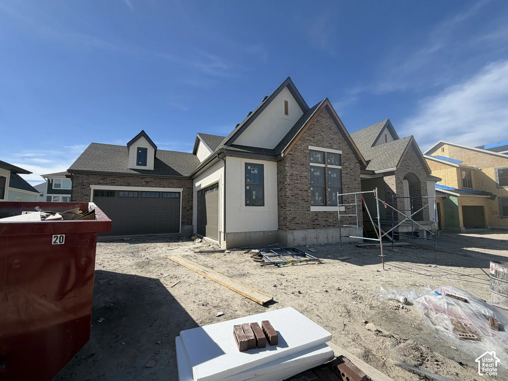 Newly constructed home featuring a striking mixed-material exterior with brick and stone accents, multiple peaked rooflines with architectural detailing, and a two-car garage