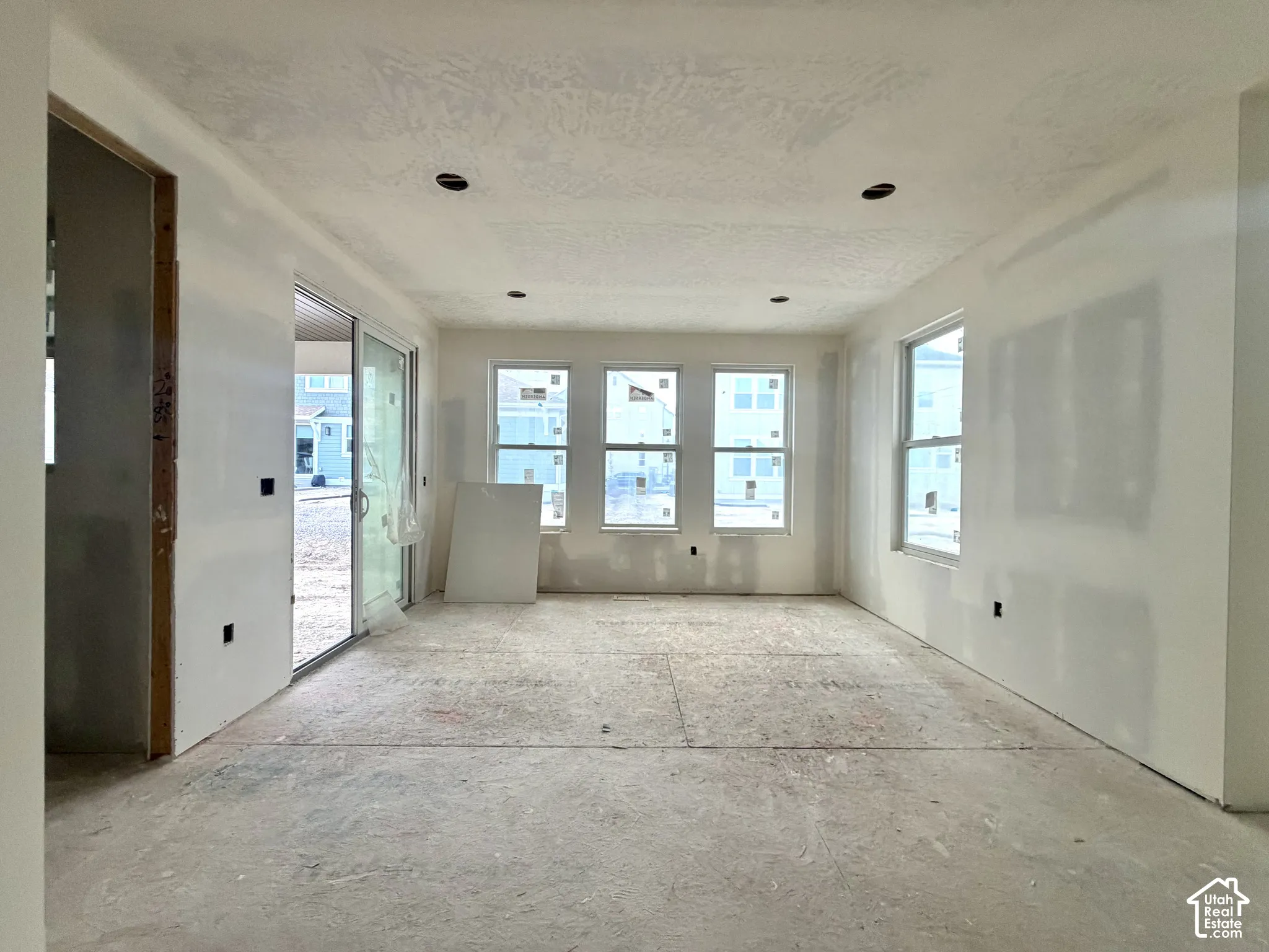 Recessed lighting, multiple windows, sliding glass door, unfinished flooring, and new drywall