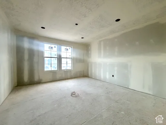 Unfinished interior space featuring two windows, recessed ceiling lighting, and exposed drywall