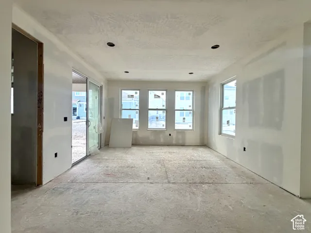 Recessed lighting, multiple windows, sliding glass door, unfinished flooring, and new drywall