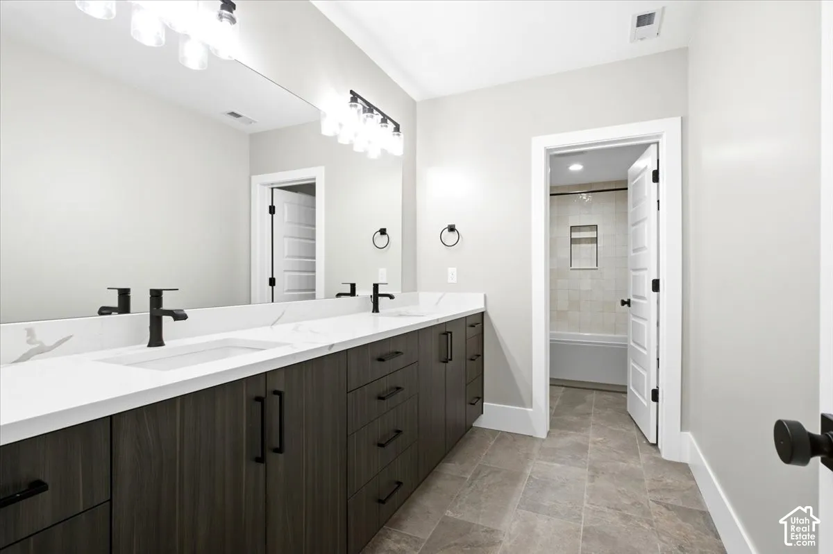 Dual vanity with wood-finish cabinetry, white countertops, and matte black fixtures