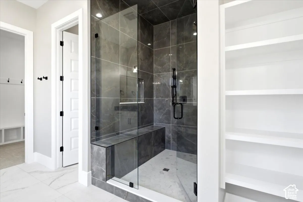 Walk-in shower with dark tile surround, built-in bench, and black fixtures