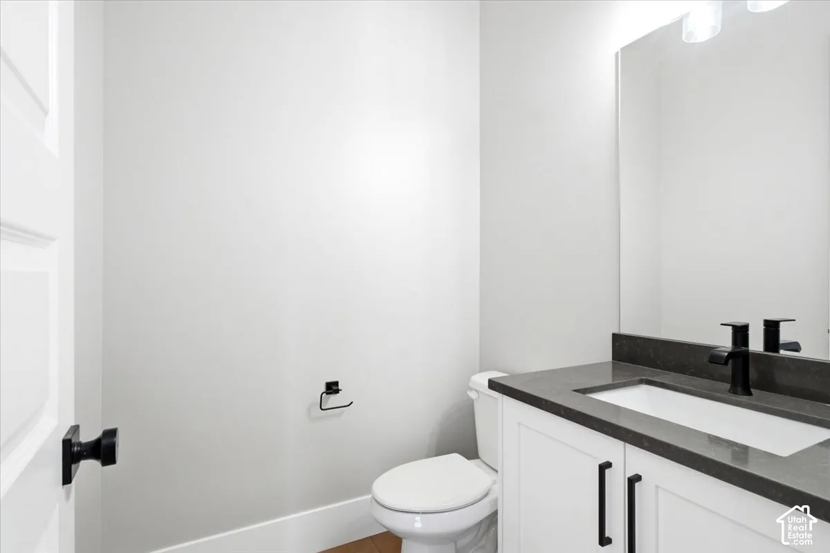Vanity with dark countertop, integrated sink, and matte black faucet