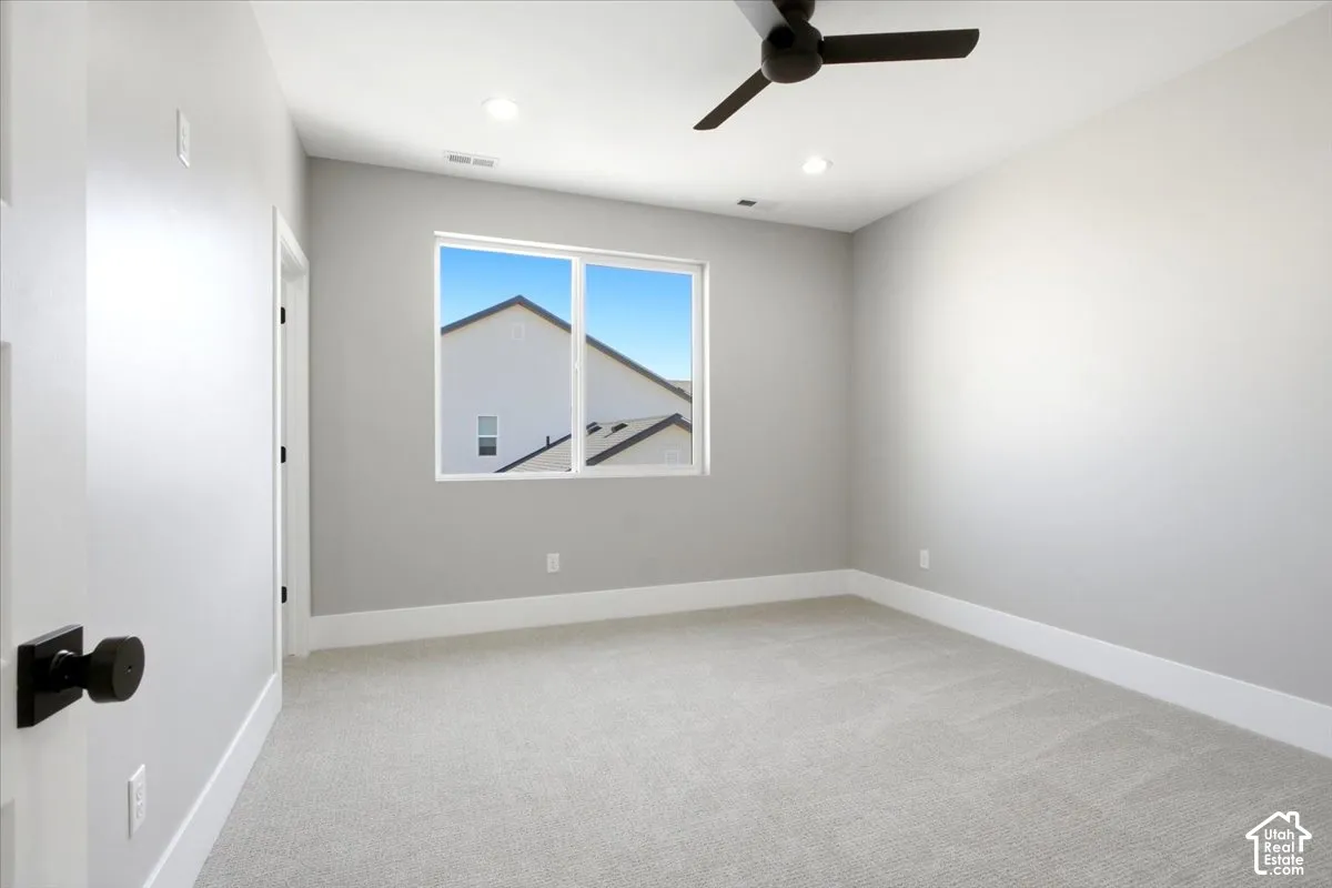 Neutral wall paint, light-toned carpeting, ceiling fan, recessed lighting, and a white-framed window