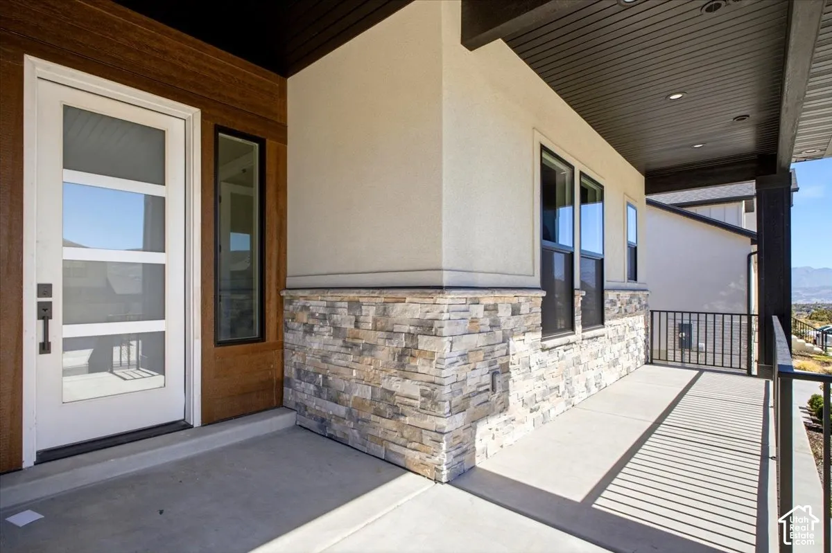 Entryway featuring a white door with multiple glass panes, a wood-look accent wall, and stacked stone siding