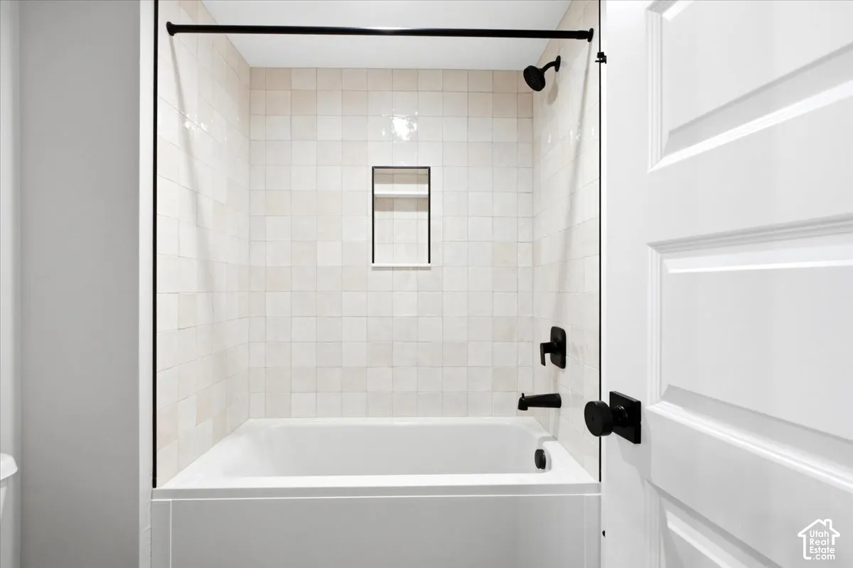 Bathtub with tile surround, integrated shower niche, and matte black fixtures