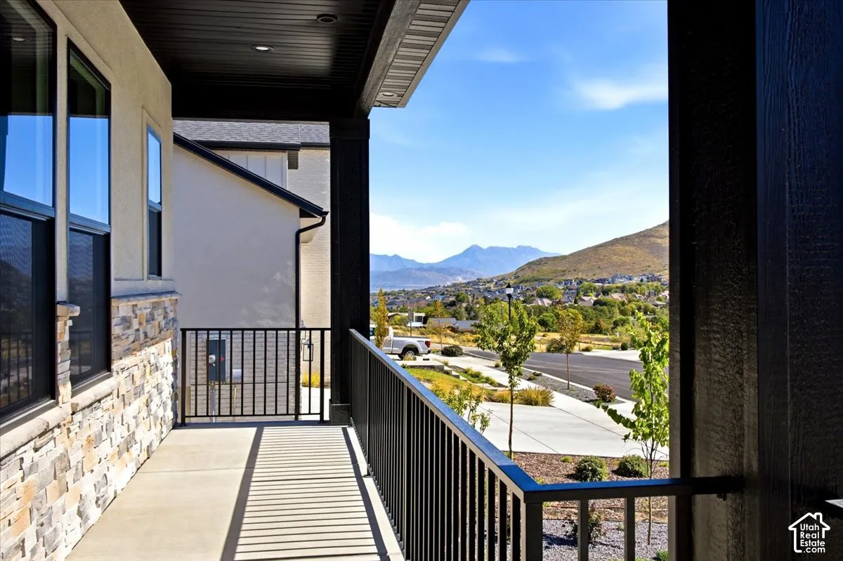 Covered concrete porch with black metal railings, stone veneer accents, and mountain scenery