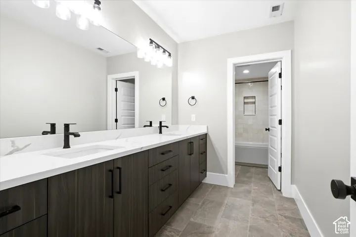 Dual vanity with wood-finish cabinetry, white countertops, and matte black fixtures
