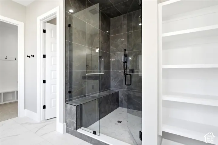 Walk-in shower with dark tile surround, built-in bench, and black fixtures
