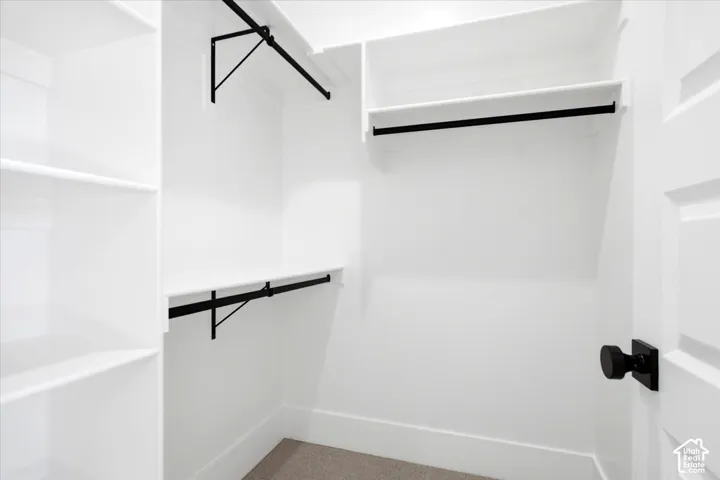 Built-in shelving, multiple hanging rods, and a neutral carpeted floor