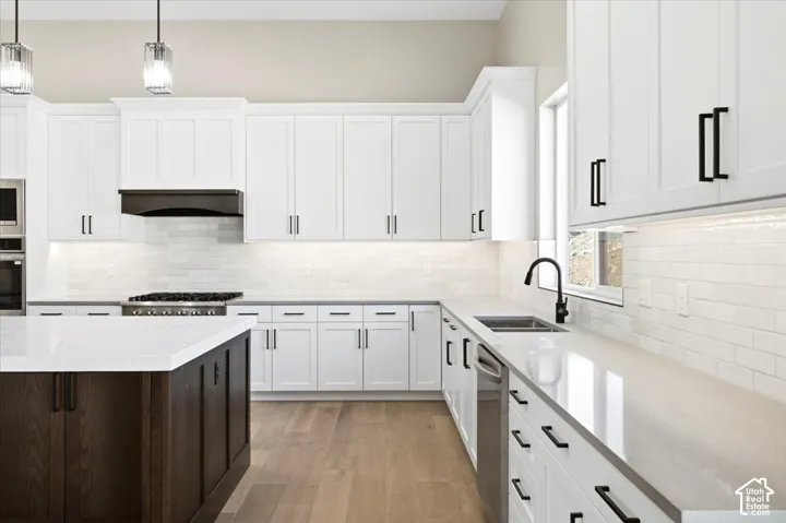 Kitchen featuring white shaker-style cabinetry, a dark wood-finish island, light-toned countertops, and wood-finish flooring