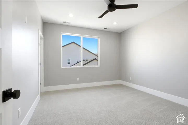 Neutral wall paint, light-toned carpeting, ceiling fan, recessed lighting, and a white-framed window