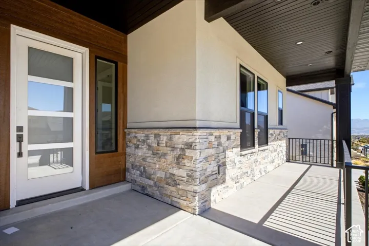 Entryway featuring a white door with multiple glass panes, a wood-look accent wall, and stacked stone siding