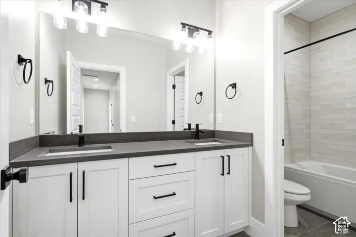 Dual vanity with white cabinetry, matte black hardware, and dark countertop
