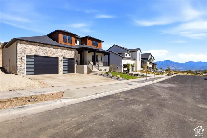 Stone veneer facade with wood-finish accents, two-car garage, and an additional single-car garage