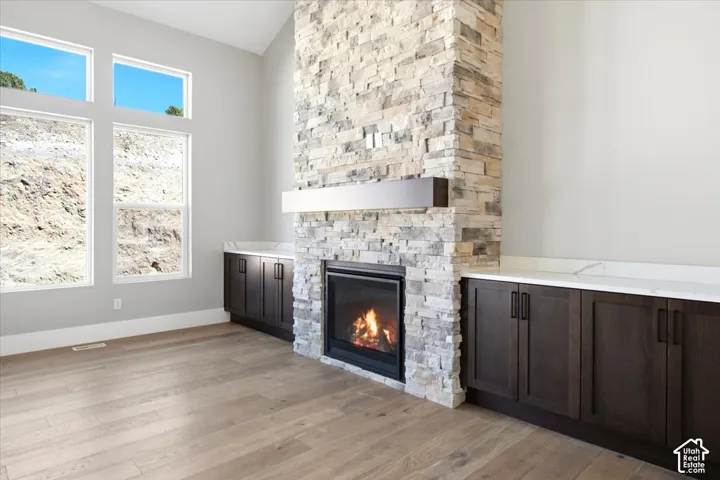 Stone-clad fireplace with a dark wood mantel, flanked by built-in dark wood cabinetry and white countertops