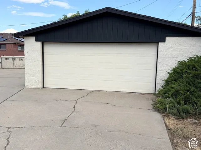 Attached garage with a white panel door, featuring a black-clad gable roof and white block exterior