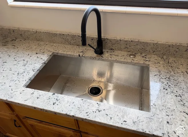 Stainless steel undermount sink set into a speckled countertop, featuring a matte black gooseneck faucet