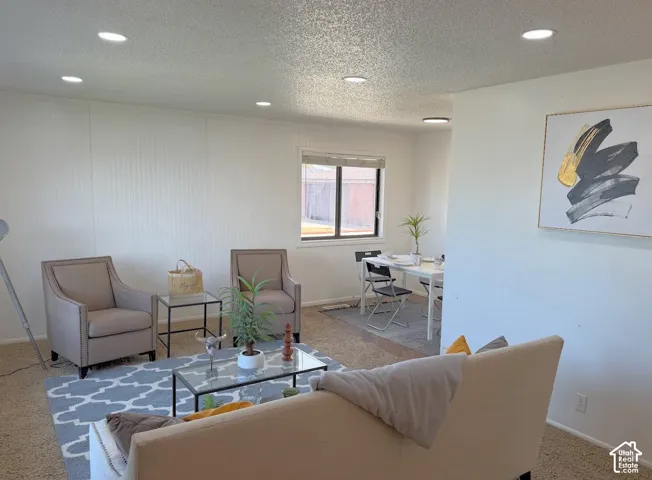 Recessed ceiling lighting illuminates a room with textured wall panels and a window overlooking exterior grounds