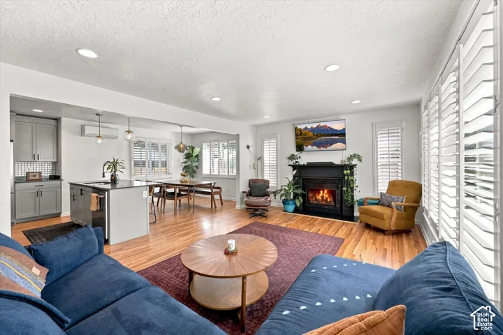 Hardwood flooring throughout, recessed lighting, and a fireplace with a black mantel