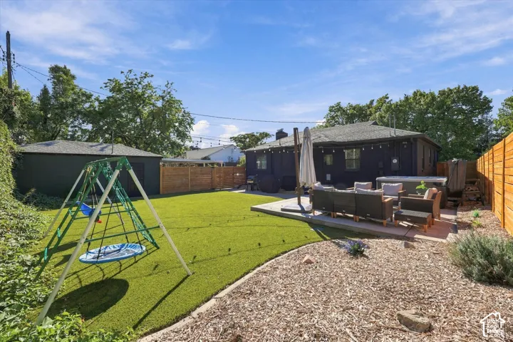 Expansive backyard featuring a manicured lawn, a separate storage shed, a wood fence, and a patio area with a hot tub