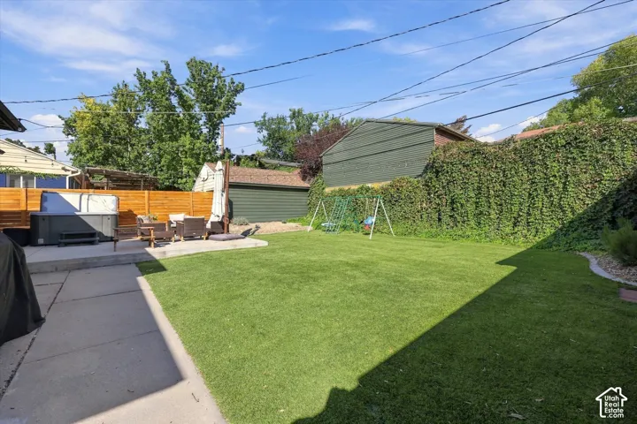 Expansive green lawn, concrete patio, privacy fencing, additional concrete pad, and mature perimeter foliage