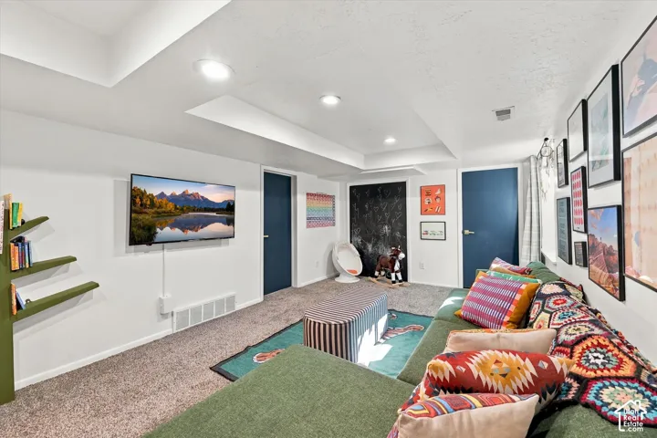 Recessed lighting illuminates the carpeted flooring and white walls