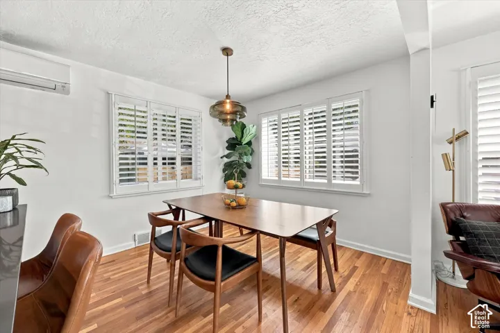 Hardwood flooring, plantation shutters, modern light fixture, and a wall-mounted air conditioning unit