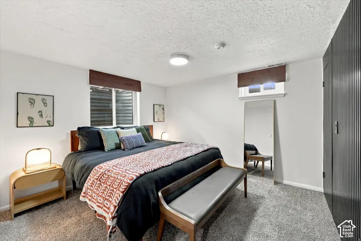 Carpeted flooring, white painted walls, and textured ceiling