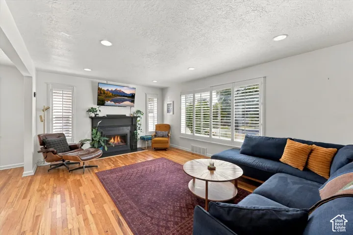 Living space featuring wood-finish flooring, recessed lighting, and a black fireplace with a white mantel