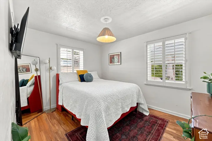 Hardwood flooring, white walls, two windows with white plantation shutters, and a suspended ceiling light fixture