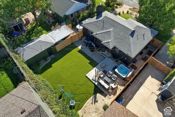 Expansive backyard featuring a manicured artificial lawn, a built-in spa, a detached shed with a covered extension, and a concrete patio
