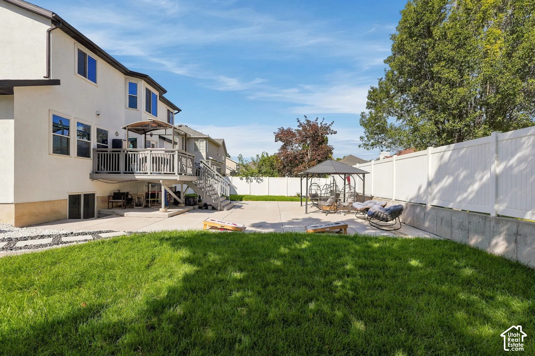 Expansive backyard featuring a manicured lawn, a large concrete patio, a multi-level deck, and a white privacy fence