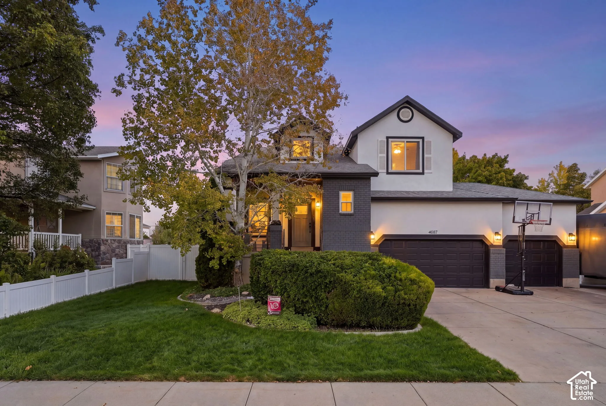 Contemporary exterior with white and dark gray siding, prominent gable dormer, and a two-car garage